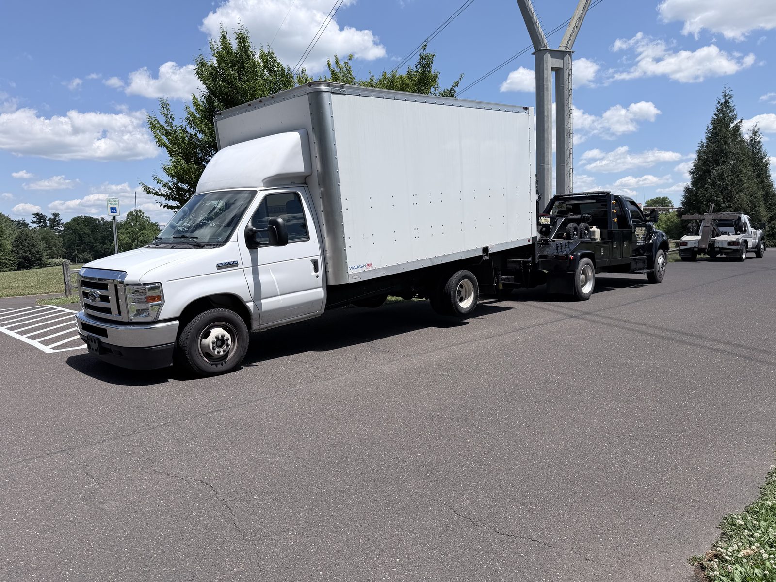 Medium-duty Chain Gang wrecker towing a commercial box truck