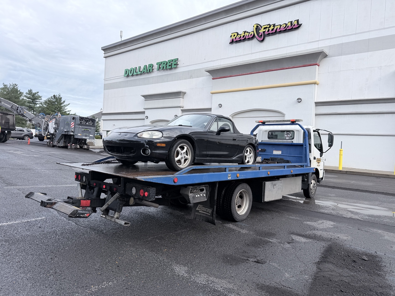 Black convertible on a Chain Gang flatbed after an authorized private-property tow in Raritan, New Jersey.
