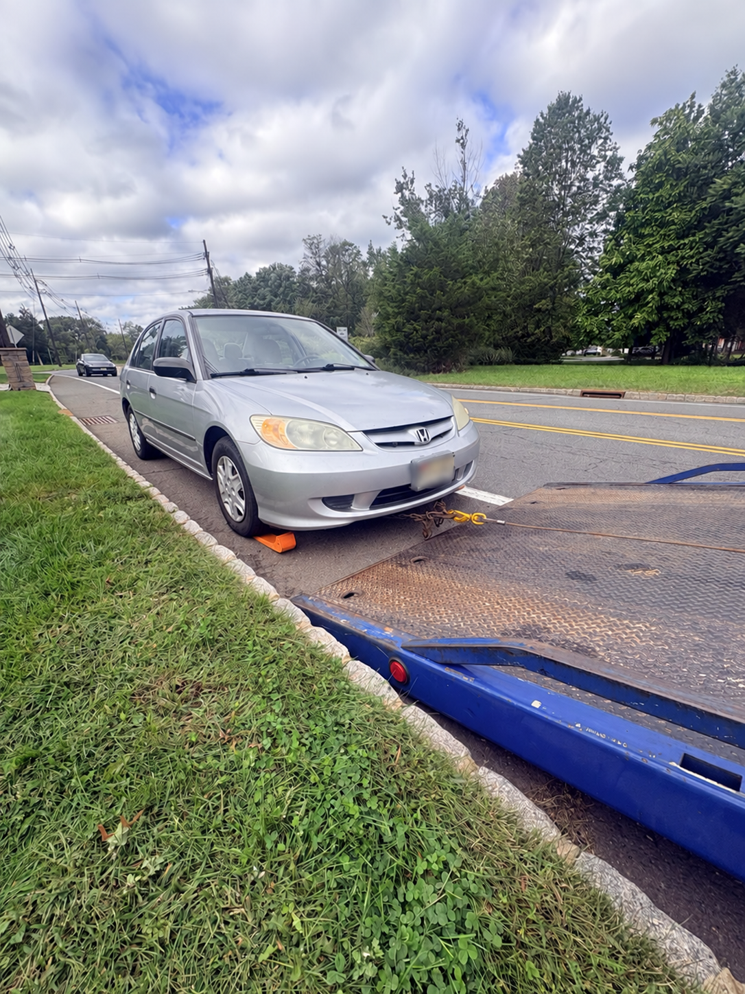 Honda Civic with a wheel skate beside a Chain Gang flatbed during controlled winch-assisted loading.