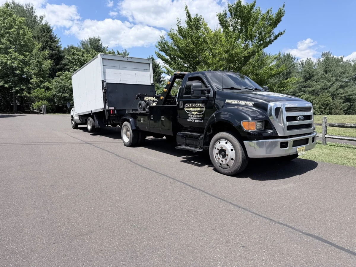 Chain Gang medium-duty tow truck transporting a box truck in Central New Jersey
